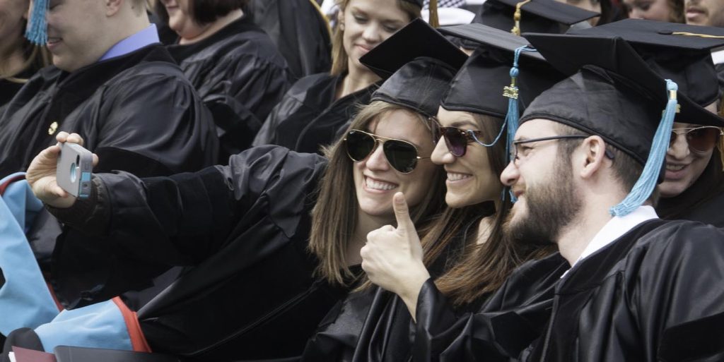 student in regalia take a selfie