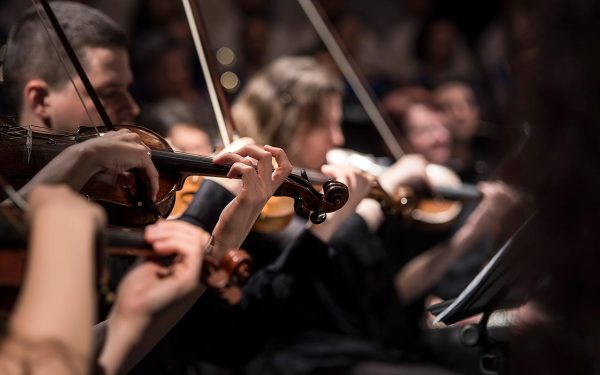 Cinematic photo of violin section in orchestra.