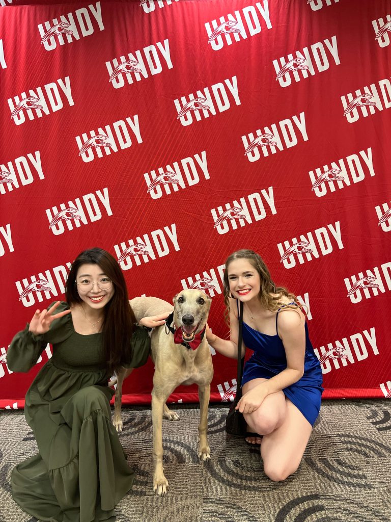 Yifan Luo poses with Grady the Greyhound and a friend
