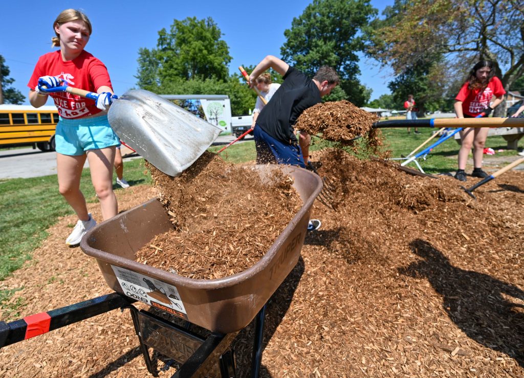 Photo of UIndy students shoveling mulch into wheelbarrows in Indy Parks