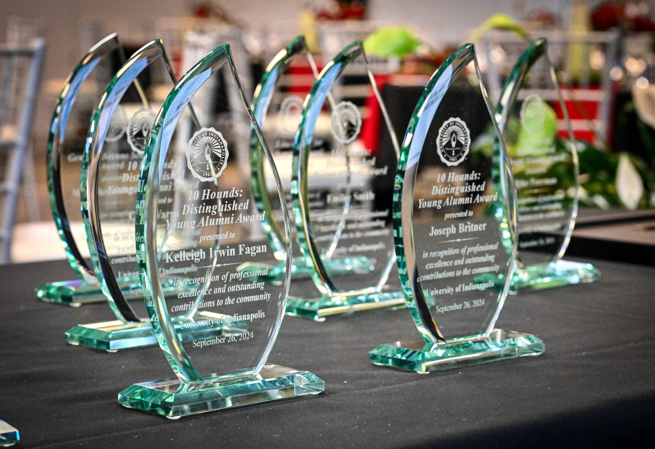 Photo of 10 glass awards for Distinguished Young Alumni on a black tabletop