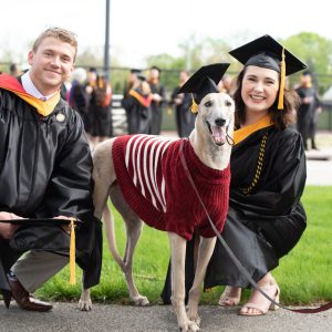 Photo of Grady the Greyhound with two UIndy graduates