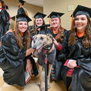 Photo of Grady the Greyhound with four UIndy graduates