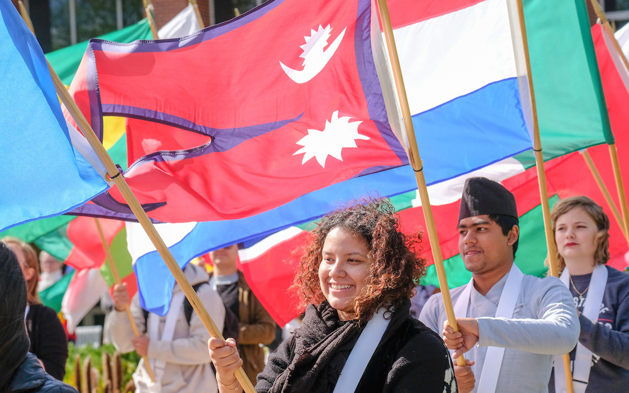 Photo of three UIndy students holding flags from their countries at UIndy Celebration of the Flags