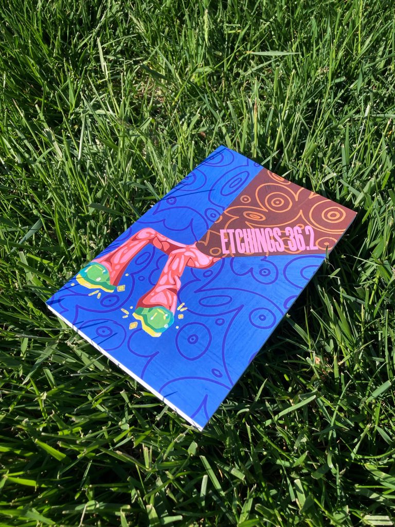 Photo of the 36.2 issue of Etchings Magazine set in the grass