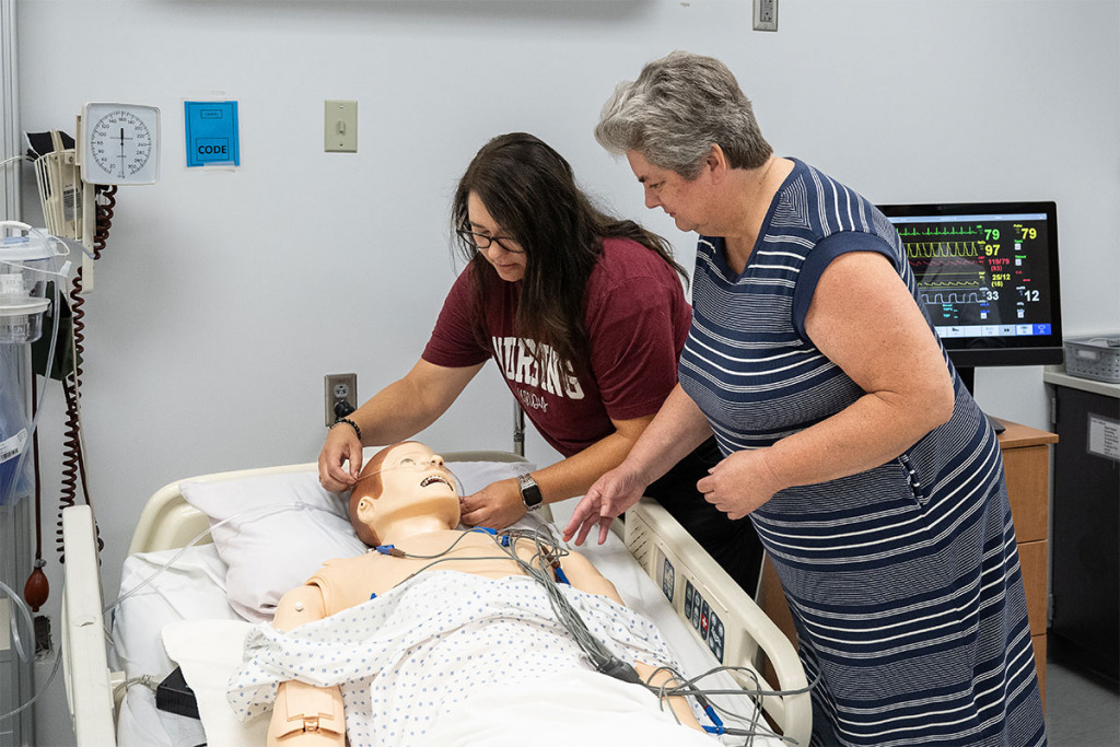 Diane Smith, right, graduate program director of the UIndy School of Nursing, oversees a nursing student in a simulation exercise. Smith says nurses are the captain of a patient’s caregiving team. (IBJ photo/Chad Williams)