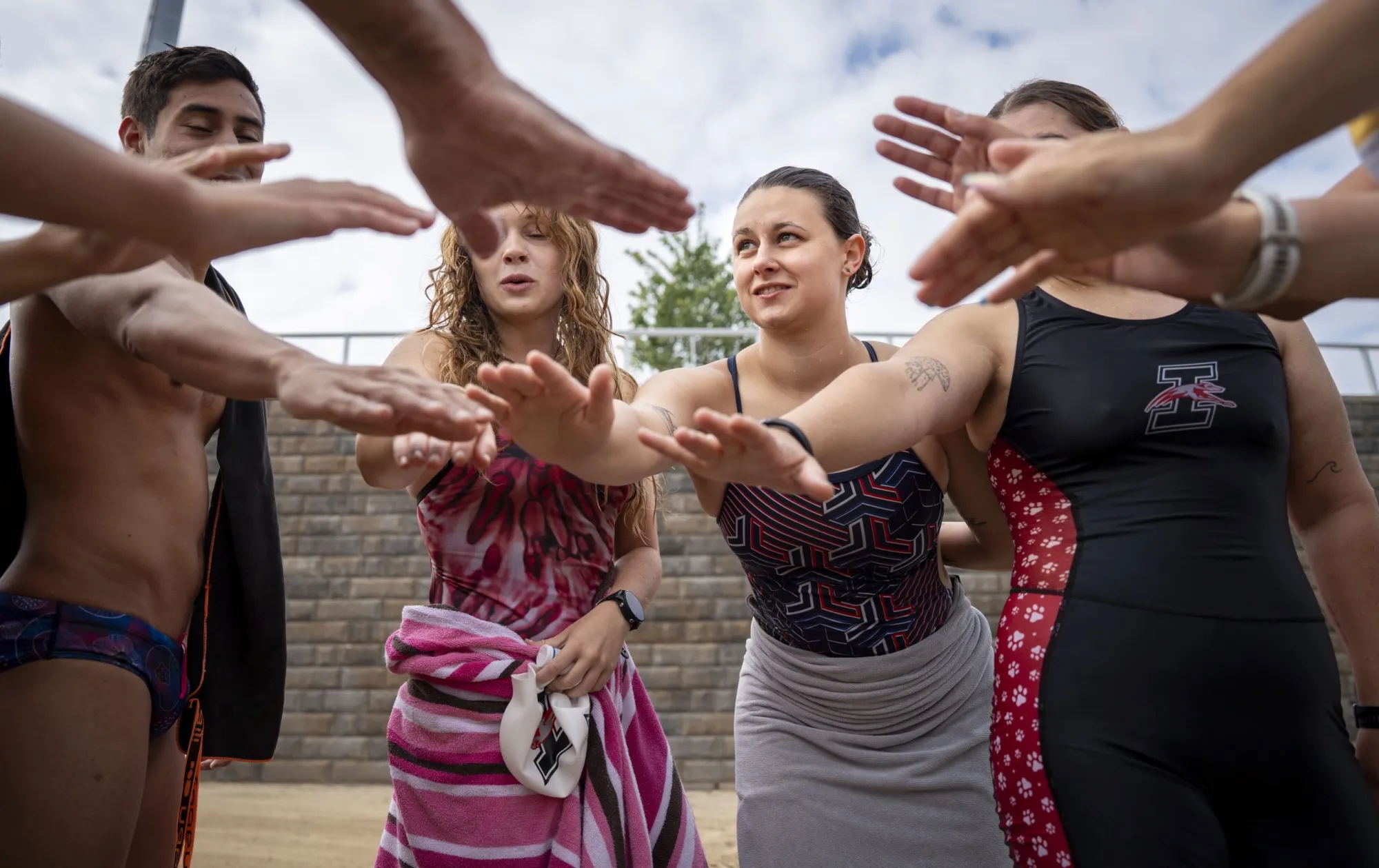 Graduate student Ainsleigh Cardone joins her team members in a group huddle after their swim practice Aug. 22, 2025, at Geist Waterfront Park in Fishers. Credit: Brett Phelps/Mirror Indy/CatchLight Local/Report for America