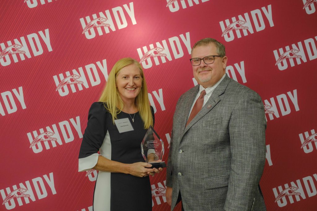 Photo of Anita Samuel receiving an outstanding alumni award from Dr. Travis Miller