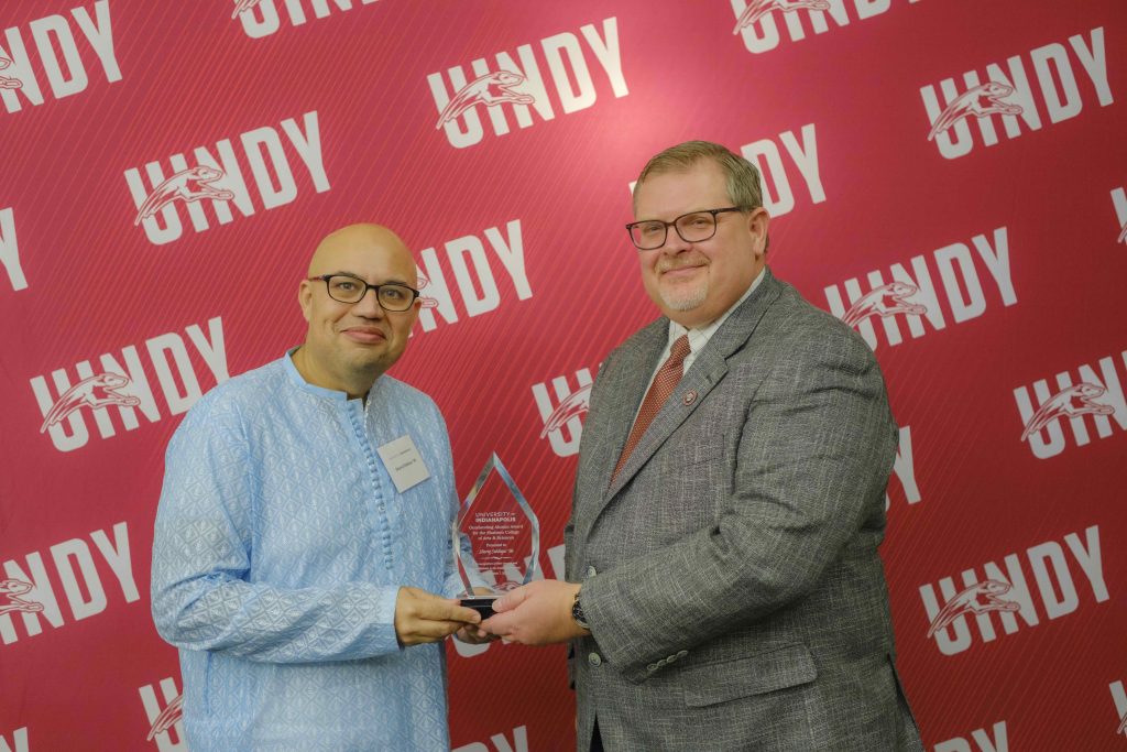 Photo of Dr. Shariq Siddiqui receiving an outstanding alumni award from Dr. Travis Miller