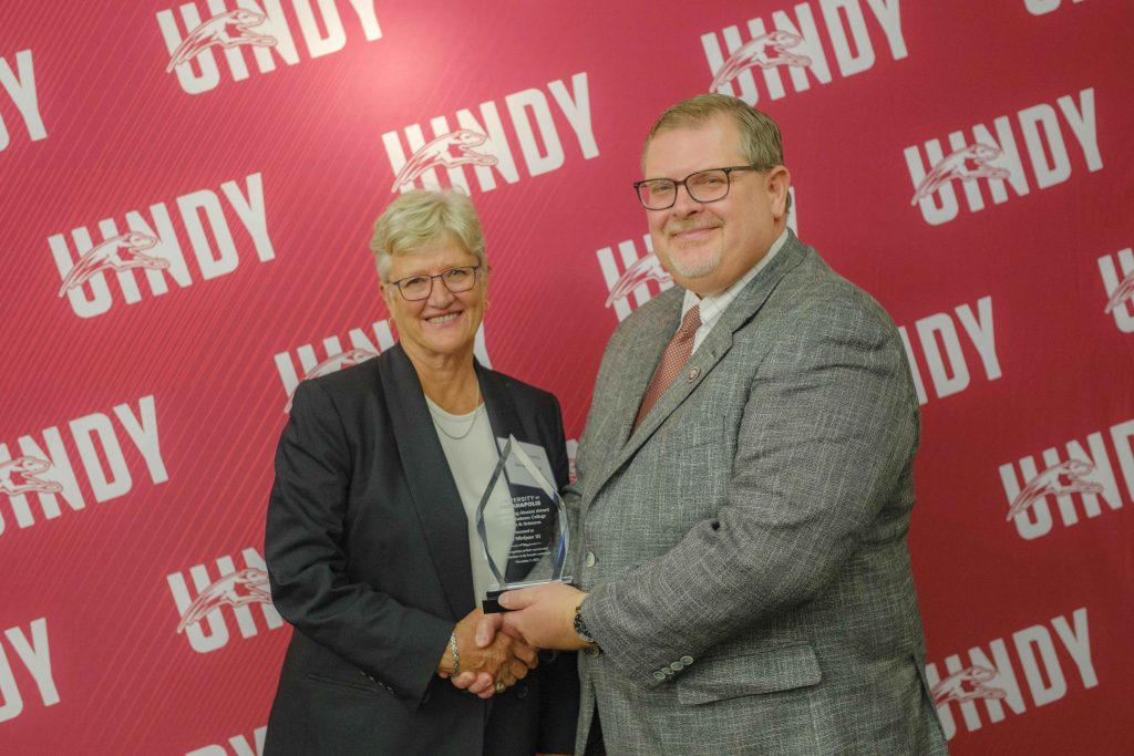 Photo of Sue Workman receiving an outstanding alumni award from Dr. Travis Miller