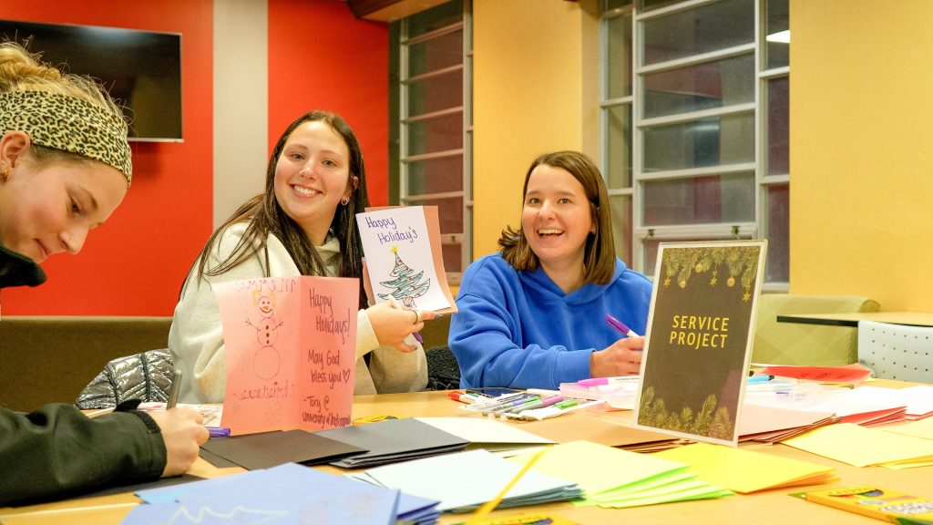 UIndy students show the holidays card they created at the Smith Mall Holiday Tree Lighting