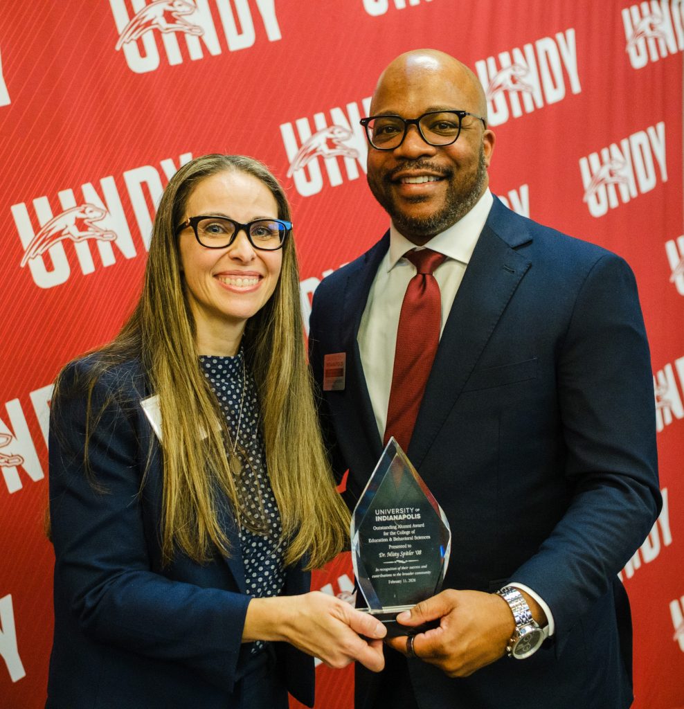 Dr. Misty Spitler holding her Outstanding Alumni Award while posing with Dr. John Kuykendall
