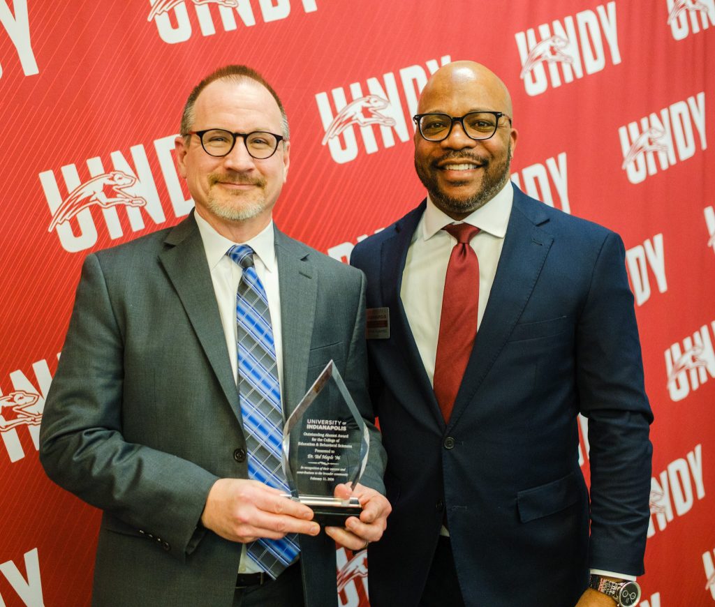 Dr. Ted Maple holding his Outstanding Alumni Award while standing next to Dr. John Kuykendall