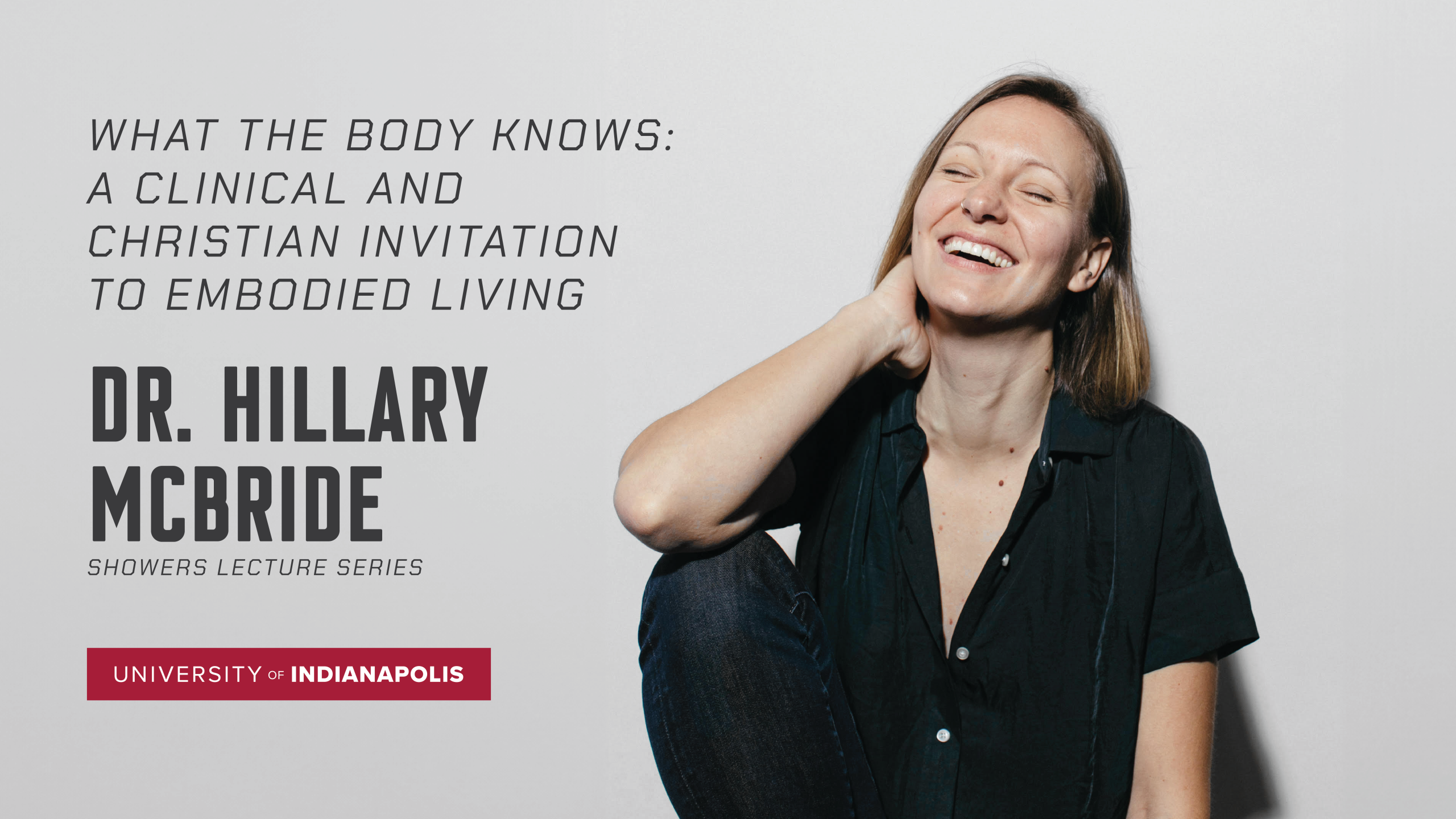 Woman smiles while posing with eyes closed and hand on neck