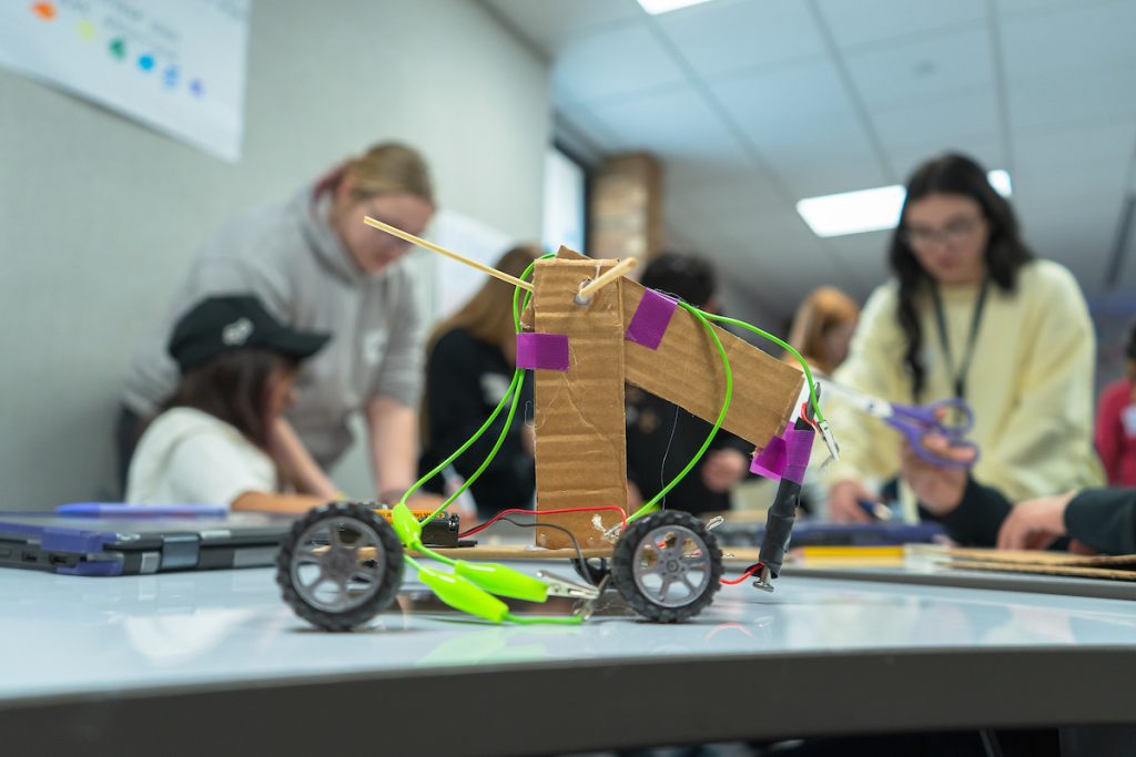 Toy/Gadget in focus on a table in a elementary school classroom with students working in the background