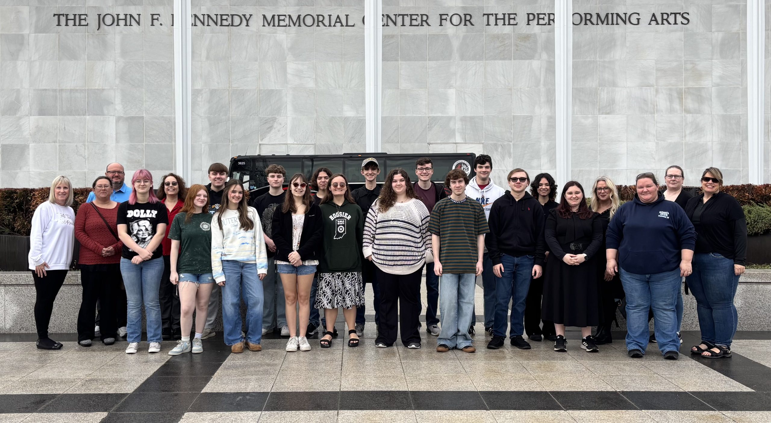 24 people lined up stand in front of John. F. Kennedy Center for Performing Arts
