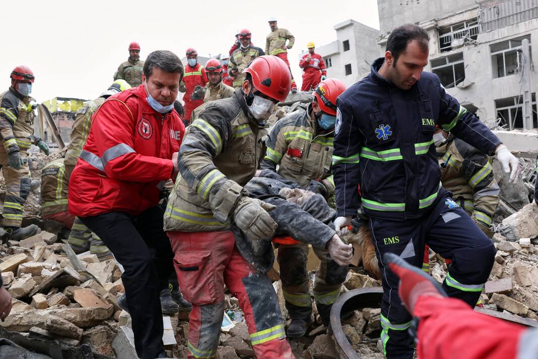 Rescue workers carry a severely injured man after pulling him from the rubble following a strike in southern Tehran, Iran, on March 13. The Associated Press