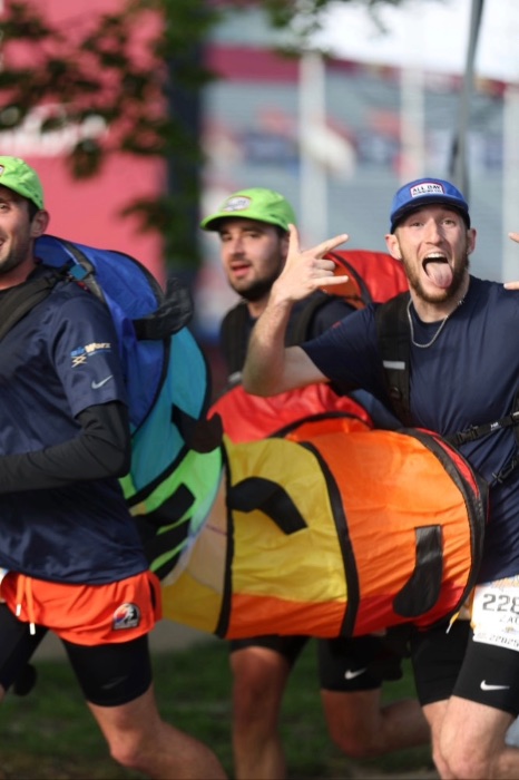 Man sticks tongue out, sporting a caterpillar costume with two other people in frame