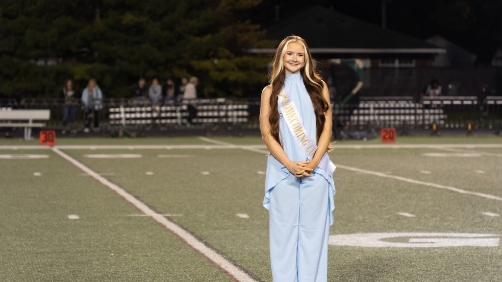 Heaven Thompson, dressed in a blue suit with a sash that reads, "Homecoming Court."