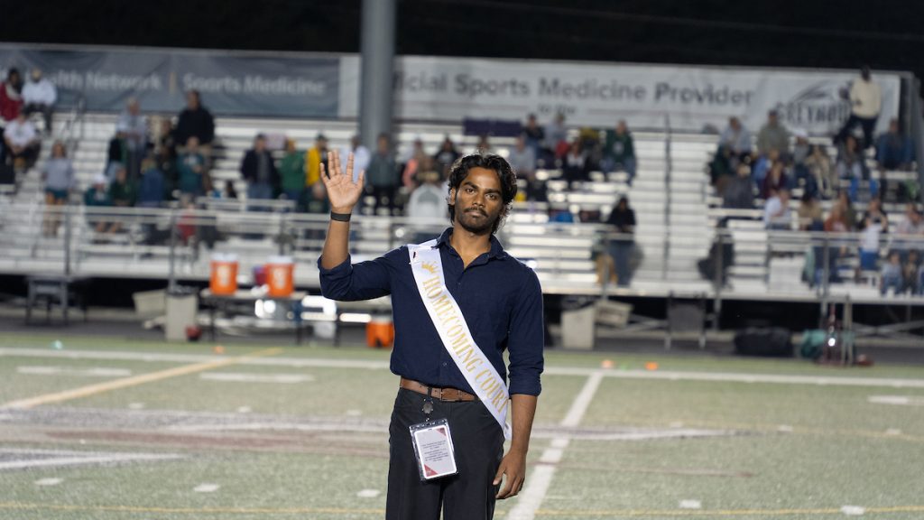 Badrinath Arul Raj, dressed in a black button down and wearing a sash that reads, "Homecoming Court."
